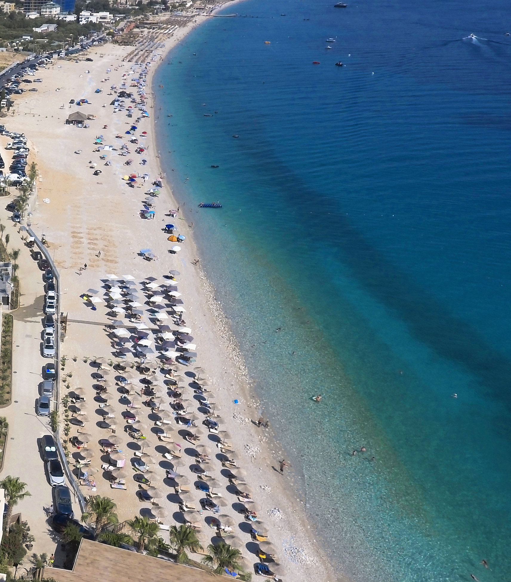 Aerial view of Drymadhes Beach with sun umbrellas and the turquoise Ionian Sea.