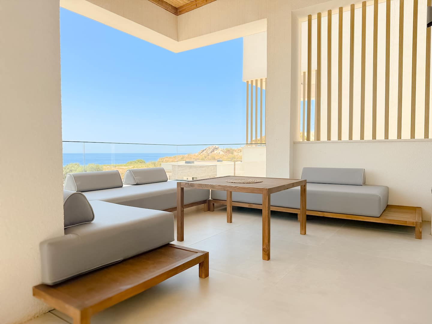 Indoor lounge at Villa 4 — linen sofa, oak table, glass doors to the veranda.