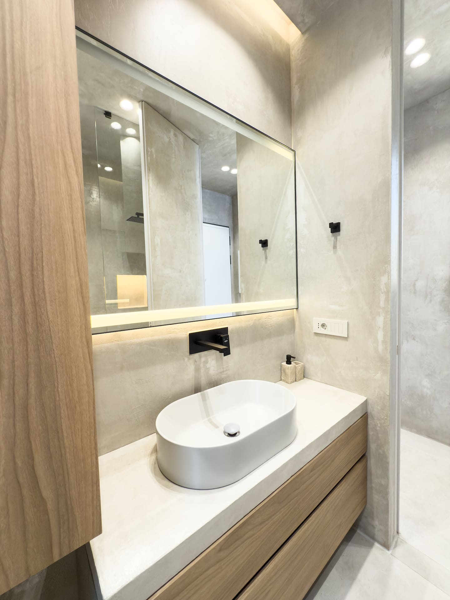 Full bathroom at Villa 4 — microcement walls and matte-black fixtures.