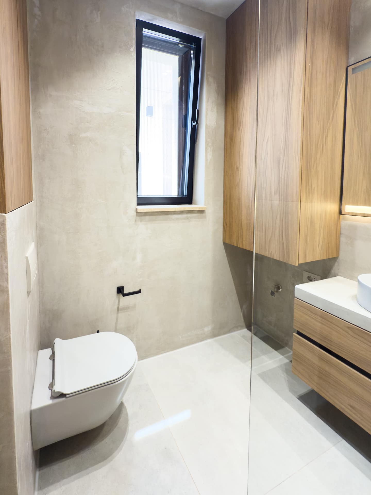 Full bathroom at Villa 4 — microcement walls and matte-black fixtures.