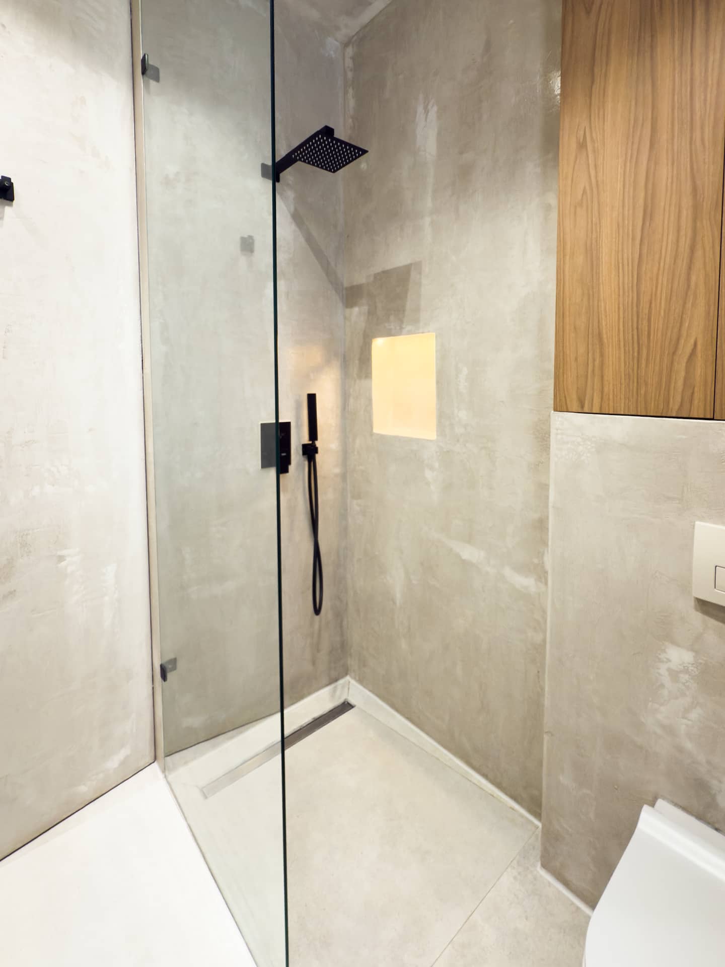 Full bathroom at Villa 4 — microcement walls and matte-black fixtures.