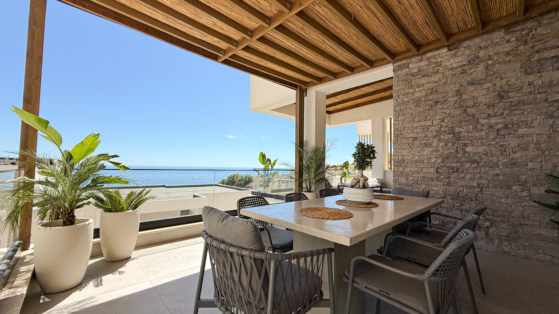 Shaded veranda dining area at Villa 4 with sea views and a long outdoor table.
